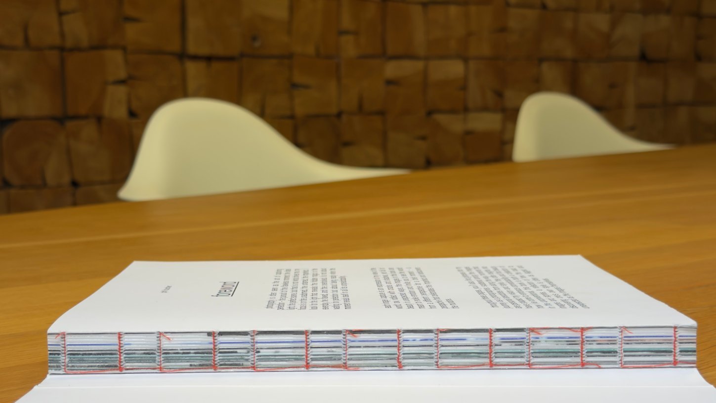 Buch mit offener Fadenheftung liegt vollständig flach aufgeschlagen auf dem Tisch